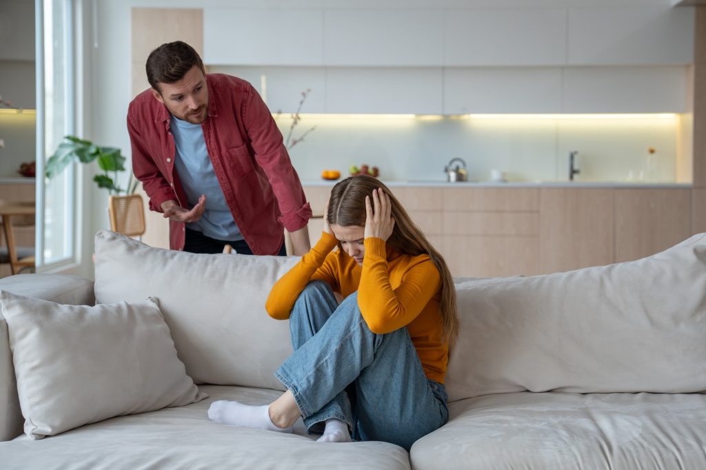Toxic communication upset woman closed ears sitting on home sofa while offended man talk in quarrel